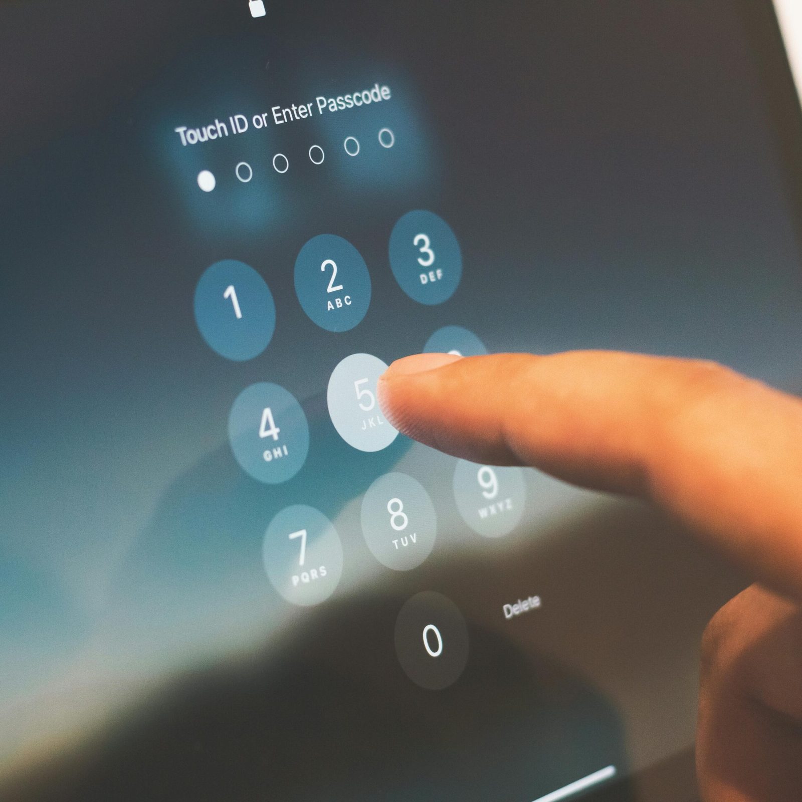 Finger pressing a numeric passcode keypad on a phone screen, with the words "Touch ID or Enter Passcode" shown above the digits